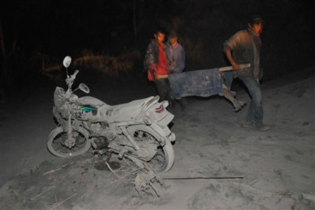 Một nạn nhân của núi lửa Merapi đang được đưa đi trong lớp tro bụi dày. Ảnh: AFP