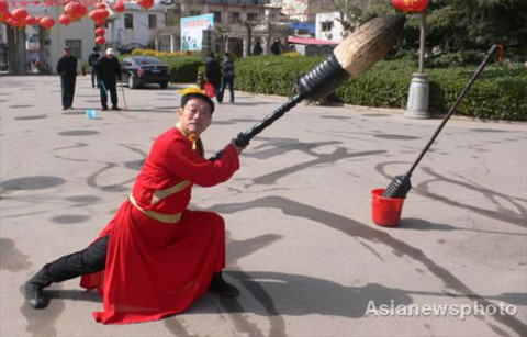 Ông Bai Desheng, 60 tuổi, kết hợp các động tác võ thuật điêu luyện để viết chữ trên mặt đất.