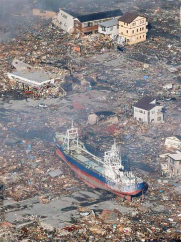 Một con tàu lớn bị sóng thần hất văng lên đường phố bên những ngôi nhà đổ nát ở thành phố Kasennuma. Ảnh