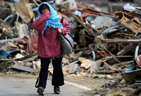 Một phụ nữ Nhật gạt nước mắt khi đi qua đống đổ nát sau trận sóng thần. Ảnh: AP.