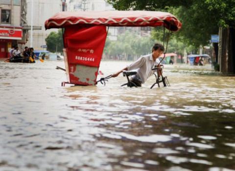 Một người đạp xe qua nước lụt ở thành phố Lan Tây, tỉnh Chiết Giang. Ảnh: AFP.