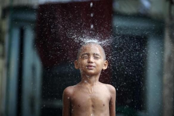 Một chú tiểu thích thú tắm mưa ở Shin Ohtama Tharya, Yangon, Myanmar.