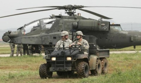Các binh sĩ Mỹ đi trên thiết bị quân sự trước một chiếc trực thăng AH-64D Apache của Tiểu đoàn tấn công trên không số 4 thuộc Lữ đoàn tấn công trên không số 2 ở căn cứ không quân Mỹ tại Gunsan.