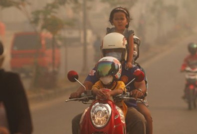 Một gia đình đi xe máy qua lớp khói mù trong thị trấn Duri ở tỉnh Riau của Indonesia, ngày 24/6/2013.