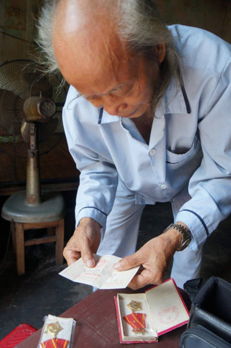 Cụ Hà Văn Ninh đang lục những hy hiệu Huân chương kháng chiến hạng Nhì mà Nhà nước phong tặng cho vợ chồng cụ vì có công.