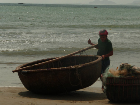 Ngư dân trẻ một mình gắng sức đưa thuyền lên bờ tránh bão.