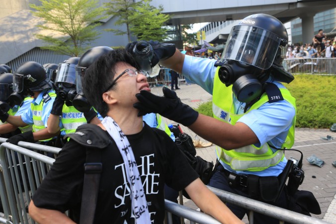 Ngày 29/9, một cảnh sát đứng trước trụ sở chính quyền lấy chai nước của mình và rửa đôi mắt cho người biểu tình vừa bị anh ta xịt hơi cay. Ảnh epochtimes.com
