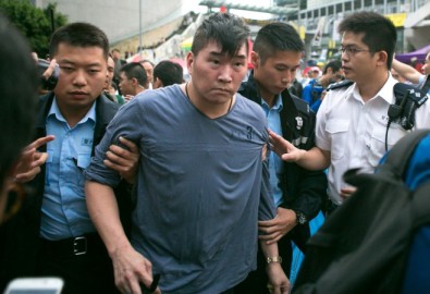 Một thủ phạm ném rác thối vào ông Jimmy Lai bị cảnh sát giải đi. (Benjamin Chasteen/Epoch Times)