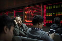 Những người giao dịch chứng khoán Trung Quốc trò chuyện trước bảng hiển thị các mã chứng khoán tại một công ty môi giới chứng khoán ở Bắc Kinh, Trung Quốc, ngày 22/1/2015. (Kevin Frayer / Getty Images)
