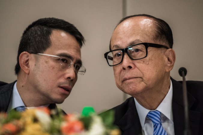 Hong Kong tycoon Li Ka-shing (R) listens to his son Victor Li Tzar-kuoi during a press conference in Hong Kong, on Jan. 9, 2015. According to democracy activist Edward Chin, Asia's richest man is feeling the pressure from Beijing. (Phillipe Lopez/AFP/Getty Images)