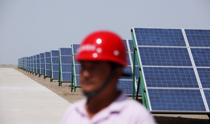 Một công nhân Trung Quốc đi bộ trong các mô-đun pin mặt trời của một dự án năng lượng quang điện kết nối với lưới điện có công suất 100MW mới được lắp đặt, vào ngày 21/7/2010 ở Đôn Hoàng, tỉnh Cam Túc phía Tây Bắc Trung Quốc. (Ảnh: Feng Li/Getty Images).