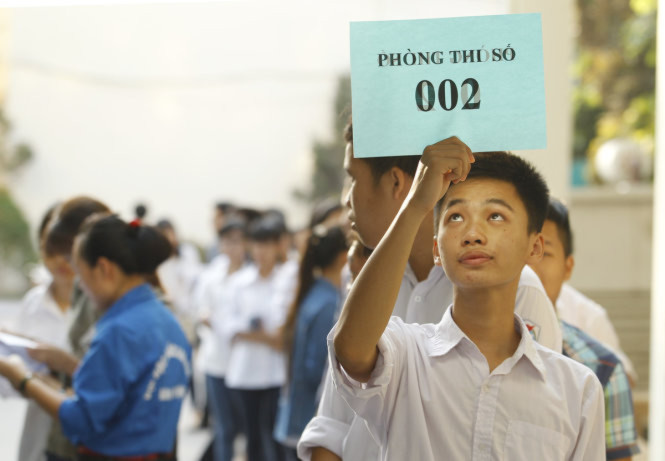 Một thí sinh cầm trên tay bảng hiệu của phòng thi tại nơi tập trung các thí sinh - Ảnh: Nguyễn Khánh