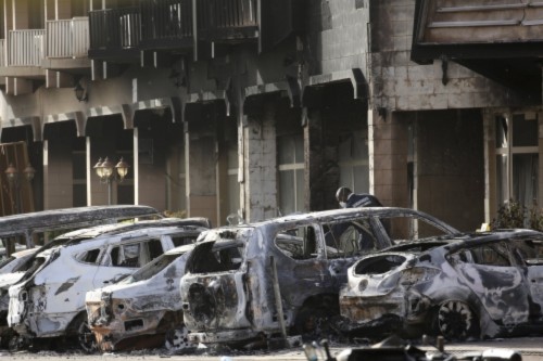 Cảnh sát xem xét những chiếc xe cháy bên ngoài khách sạn Spledid ở Burkina Faso, nơi phiến quân chiếm đóng trước khi bị tiêu diệt. Ảnh: Reuters