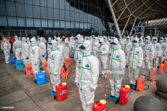 TOPSHOT - Staff members line up at attention as they prepare to spray disinfectant at Wuhan Railway Station in Wuhan in China's central Hubei province on March 24, 2020. - China announced on March 24 that a lockdown would be lifted on more than 50 million people in central Hubei province where the COVID-19 coronavirus first emerged late last year. (Photo by STR / AFP) / China OUT (Photo by STR/AFP via Getty Images)